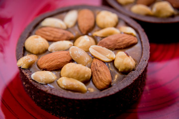 Chocolate cookies with almond nuts on a red plate. Restaurant.