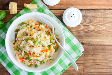 Italian risotto with vegetables - peas, beans, carrots, peppers on a white plate, selective focus