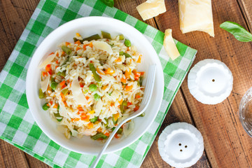 Italian risotto with vegetables - peas, beans, carrots, peppers on a white plate, selective focus