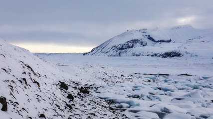 Fototapeta na wymiar Glacier tongue between mountains road to the sea on a cloudy winter day