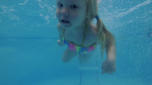 Little baby girl swimming underwater in the pool