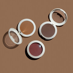 Three pressed powder contouring products on tan beige background flat lay.