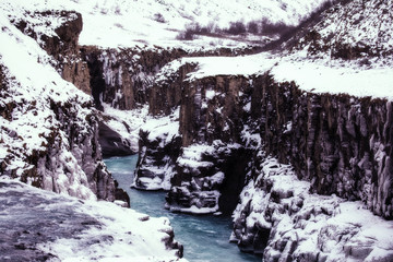 Fototapeta na wymiar Meander of the Gullfos waterfall in Iceland, surrounded by ancient rock formations on the way to the mouth