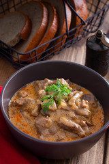 Traditional beef stroganoff in a ceramic bowl on a wooden table, selective focus