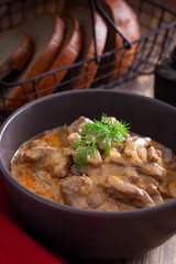 Traditional beef stroganoff in a ceramic bowl on a wooden table, selective focus