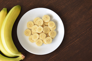 Banana on a white plate on wood table with copy space on the right side. Selective focus. 