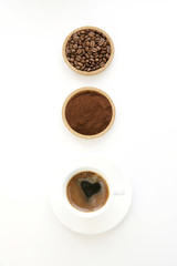Obraz na płótnie Canvas cup of black coffee with roasted grains or beans and ground coffee on a white background. The sequence of preparation of the drink. Coffee concept. Copy space. Flat lay. Top view.