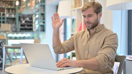Video Chat on Laptop by Young Man in Cafe