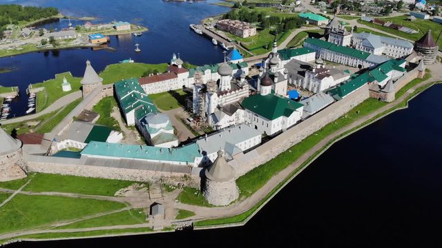 Smooth cinematic flyby of the Solovetsky monastery from the side of the Holy Lake with a view of the White Sea on a clear sunny day. Solovetsky monastery is an old (1420) ROC monastery.