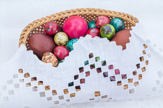 Basket of straws with Easter eggs painted in different colors and different sizes  on a tablecloth