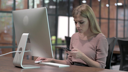 Young Woman using Smartphone while sitting on Office Desk