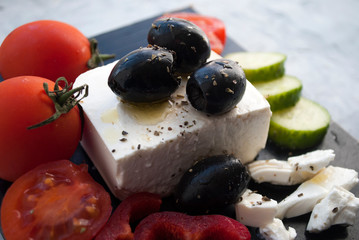 Greek feta cheese with thyme and olives, cherry tomatoes, bell pepper and cucumber. Selective focus.