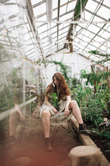beautiful girl in a light sundress poses in a greenhouse. a tropical forest. fashion photo shoot