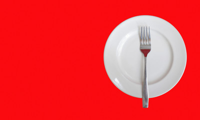 Stainless folk on white dish with red background