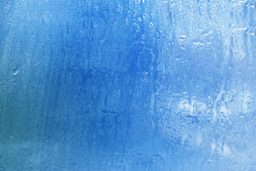 The surface of a foggy window glass with raindrops. Background. Bad weather, rain.