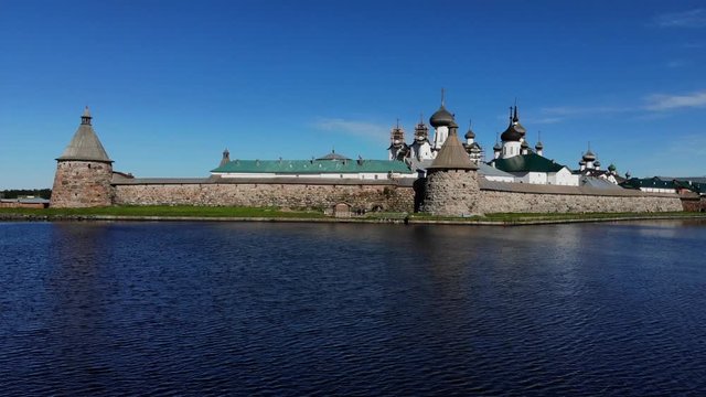 Smooth cinematographic shooting of the Solovetsky monastery from the side of the Holy Lake almost from the surface of the water on a clear sunny day.