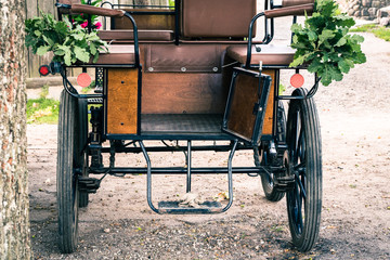 old horse-drawn carriages under the tree in summer; vintage effect