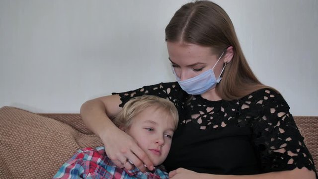 A caring mother in a bandage measures the temperature of her son.