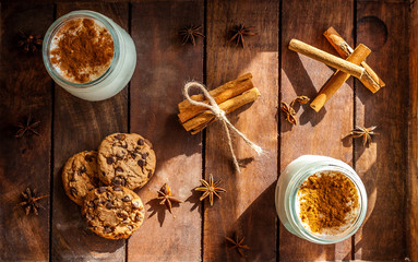 A cup of hot, turkish Sahlep on a rustic surface with cinnamon sticks and cookies