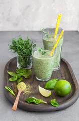 Healthy breakfast with green smoothie with matcha powder tea in glasses and ingredients on a wooden...