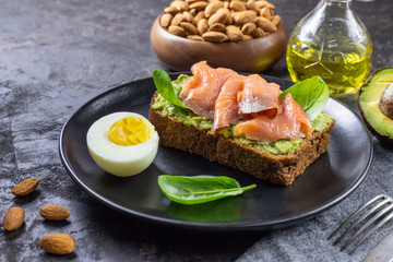 Sandwich with smoked salmon, avocado cream, fresh basil. Healthy nutrition. Concept for healthy snack. Close up.
