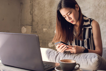A woman is using notebook while drinking coffee