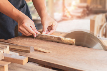 carpenter using a circular saw cutting a plank of wood working in workshop at home