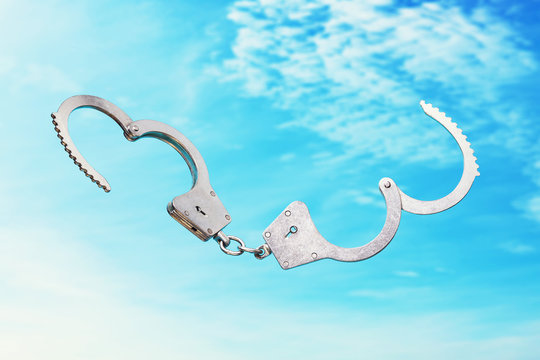 Open handcuffs on a sky background as a symbol of freedom