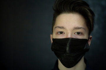 Portrait of a brown-eyed teenager in a black medical mask. Antivirus protection.