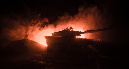 War Concept. Armored vehicle silhouette fighting scene on war foggy sky background at night.