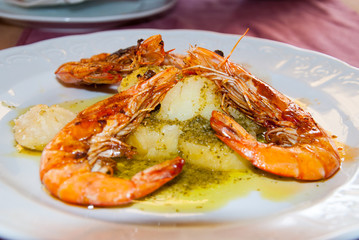 Shrimps in garlic sauce with boiled potatoes on a plate