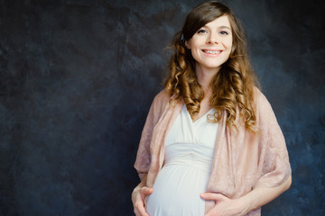 Fototapeta na wymiar Beautiful pregnant young woman on dark background. Maternity wear concept, new life, happy pregnancy.
