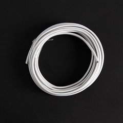 White electric cable rolled into a circle on a black background.