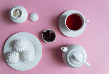 Obraz na płótnie Canvas Dry hibiscus tea petals, teapot, cup, dessert, sugar on pink background