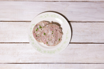 Head cheese slices on plate with herb on wooden rustic background