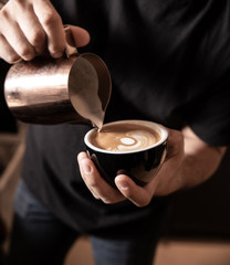 barista make latte art poring coffee in cafe