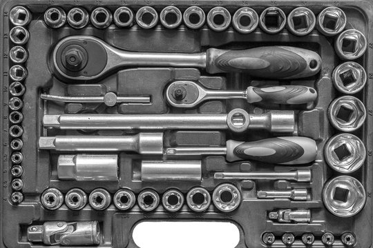 Black and white men tools background. Worker tools and equipment close-up. A set of wrenches and screwdrivers are laid out in the cells of the box.