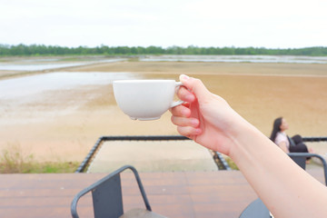 Hands holding coffee cup on farm background.Close up.