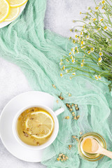 herbal chamomile tea, honey, lemon and fresh daisy flowers on blue background