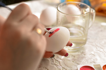 Easter egg coloring. A woman paints with a brush on an Easter egg