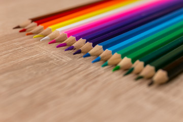 A number of colored pencils in a row on wooden background. Colorful photograpphy. Selected focus on purple.