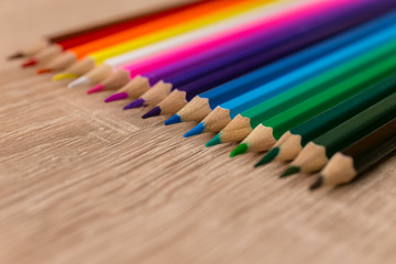 A number of colored pencils in a row on wooden background. Colorful photograpphy. Selected focus on blue.