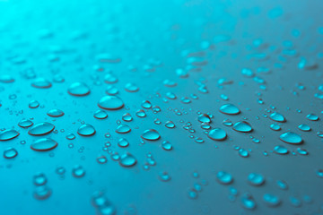 Many different drops of water rain on a blue background, close up