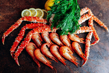 On the table are shrimp, crab, lemon and herbs. Table of reddish color.