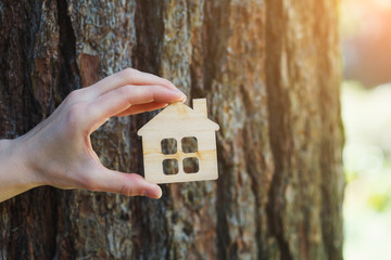 small wooden house against old tree bark, natural sunny  bokeh background, copy space, safe, sweet and ecological home concept, eco friendly accomodation