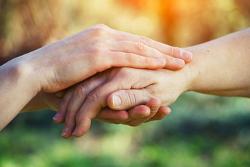 helping hands for aged people, rehabilitation, hospice and nursing home care, service, elderly people care concept, young female hands holding wrinkled hand of senior woman