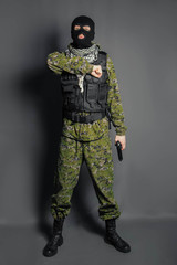 A member of the special police squad, takes aim, holds a pistol. Dressed in a balaclava,  camouflage uniform, bulletproof vest. Special weapons and tactics. Special Forces.SWAT.