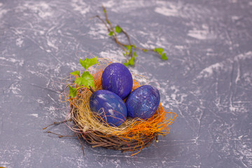 Three blue space easter eggs in a nest on a gray background. Selective focus. Copy space