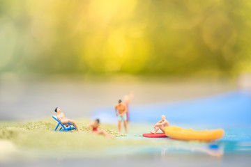 Miniature people, travelers relaxing on the sand box decorating in summer theme using as background travel, exploring the world, budget trip concept.
