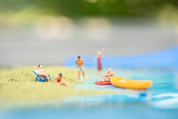 Miniature people, travelers relaxing on the sand box decorating in summer theme using as background travel, exploring the world, budget trip concept.
